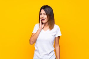 young woman with toothache, example of someone needing treatment for a broken dental crown