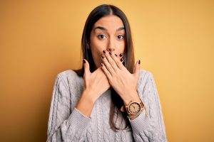 scared of a cavity, woman covering mouth to hide teeth