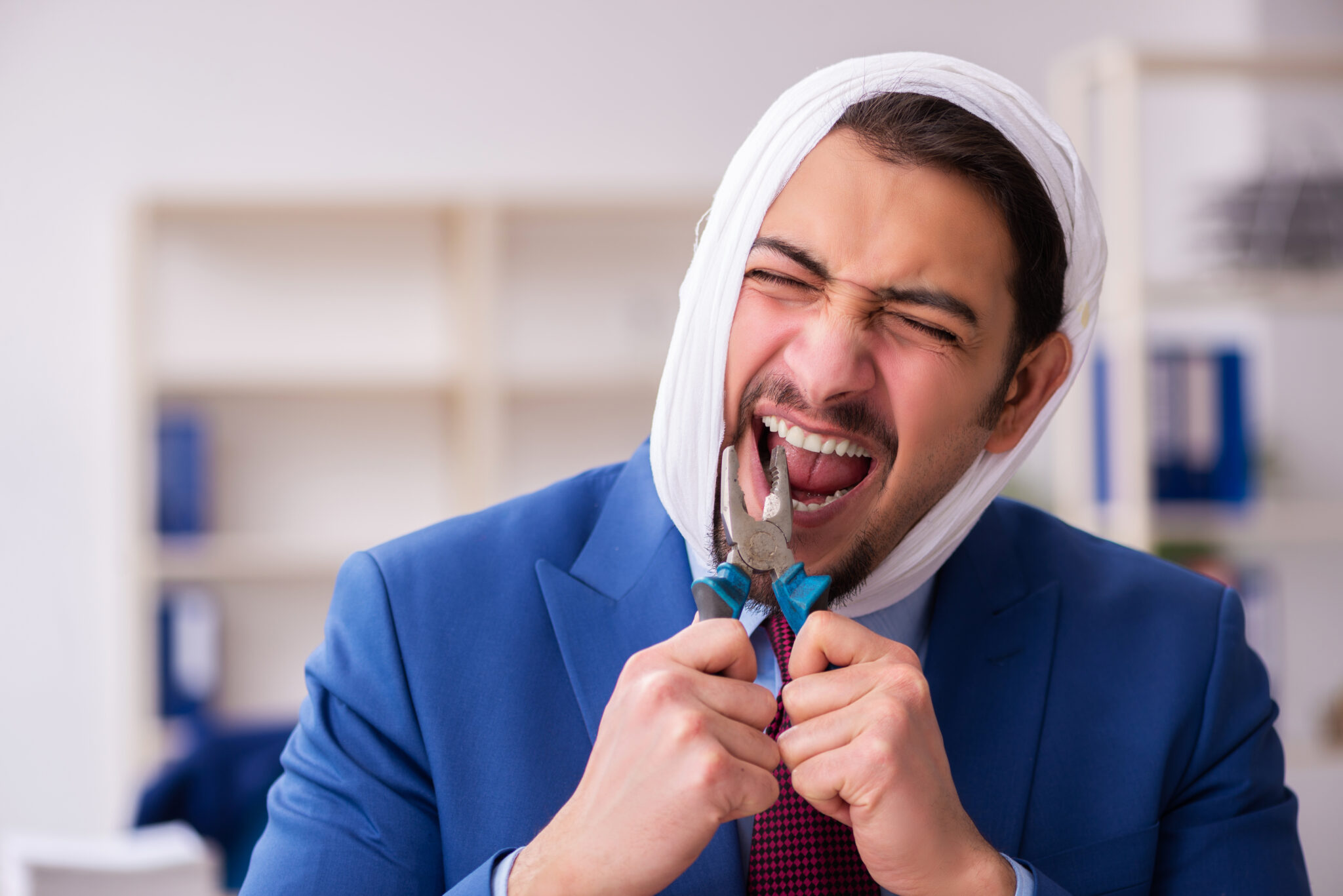 Man suffering from toothache with pliers in mouth